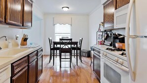 Una cocina con armarios de madera, un refrigerador blanco, una estufa y una mesa de comedor con sillas.