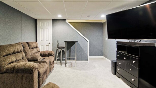 Una habitación con un sofá modular, un televisor, una mesita y una escalera.