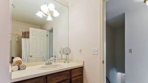 Un baño con un espejo grande, un lavabo y armarios de madera.
