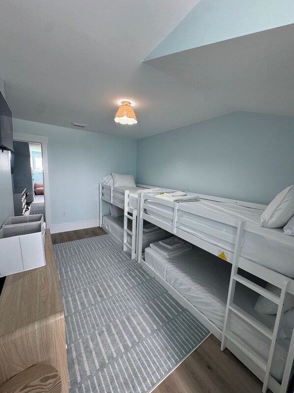 A room with bunk beds, a desk, and a patterned rug.