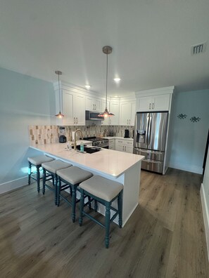 A modern kitchen with white cabinets, stainless steel appliances, and a central island with bar stools.
