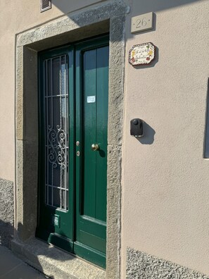 A green door with a metal gate, a small plaque above it, and a mailbox on the wall. - Apartment with a private garden and ocean view, near hiking trails (Corniglia)
