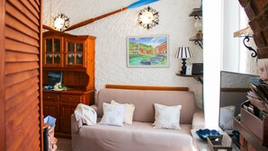 Una habitación acogedora con un armario de madera, un sofá con cojines, un cuadro en la pared y una lámpara.