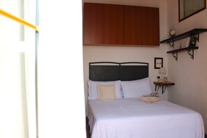 A bedroom with a bed, a nightstand, a lamp, a shelf with books, and a framed picture on the wall. - Apartment with a private garden and ocean view, near hiking trails (Corniglia)