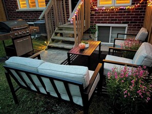 A patio with outdoor furniture, a grill, and decorative lights.