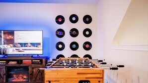Een kamer met een tafelvoetbaltafel, een televisie en een muur vol vinylplaten.
