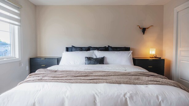 Een slaapkamer met een bed, nachtkastjes, een lamp en een op de muur bevestigd decoratie van een stierhoofd.