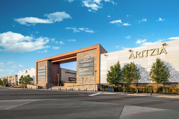 A modern building with a prominent sign reading 'ARITZIA' and a sign for 'Polo Ralph Lauren Coach UGG Boss Hugo Boss.'