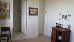 Una habitación con una puerta, una silla, un armario con objetos y decoración en la pared.