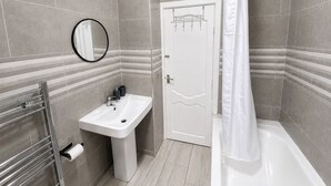 Un baño con lavamanos, espejo, toallero y cortina de ducha.