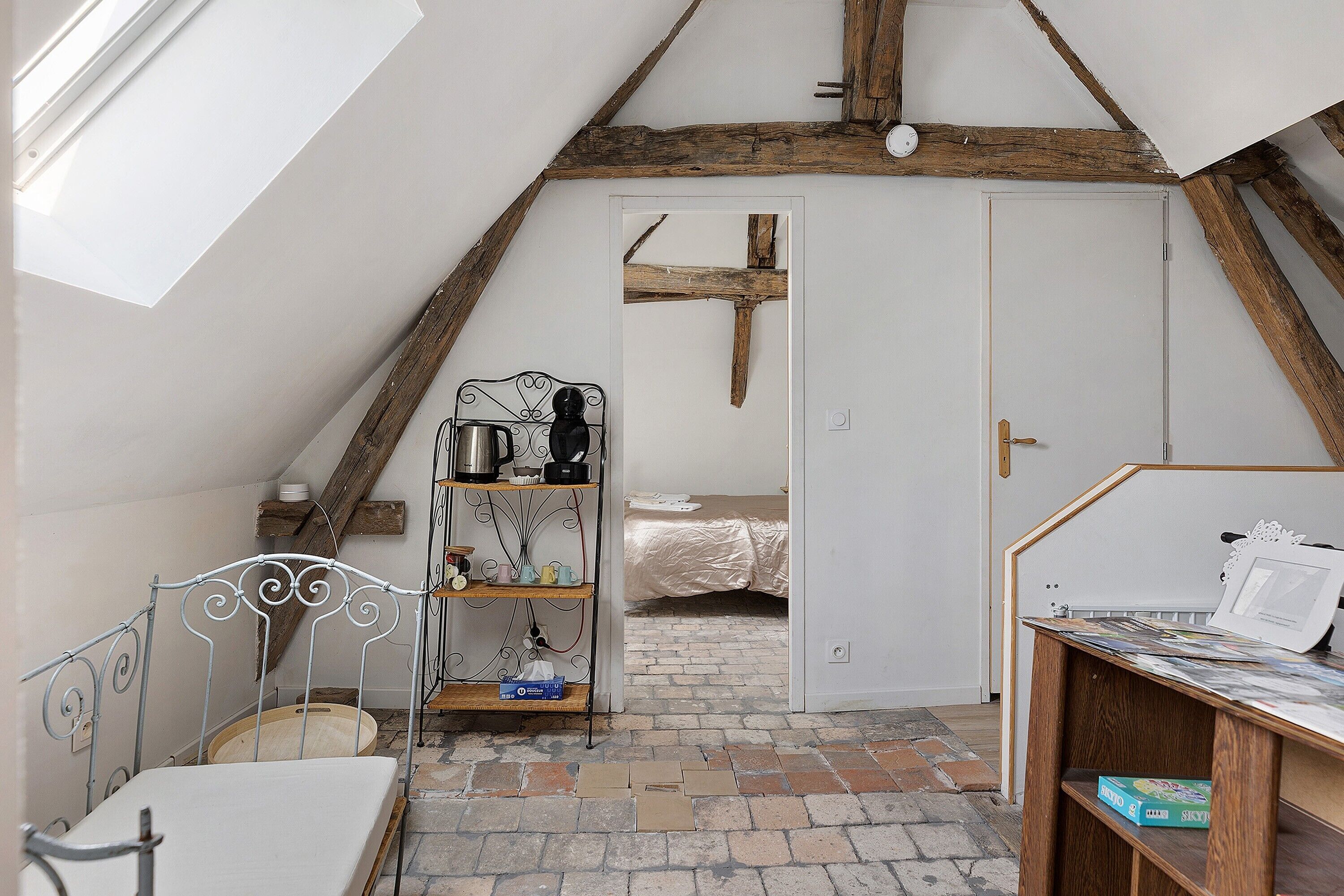 A room with a sloped ceiling, a bed, a metal shelf unit, and a table with books.