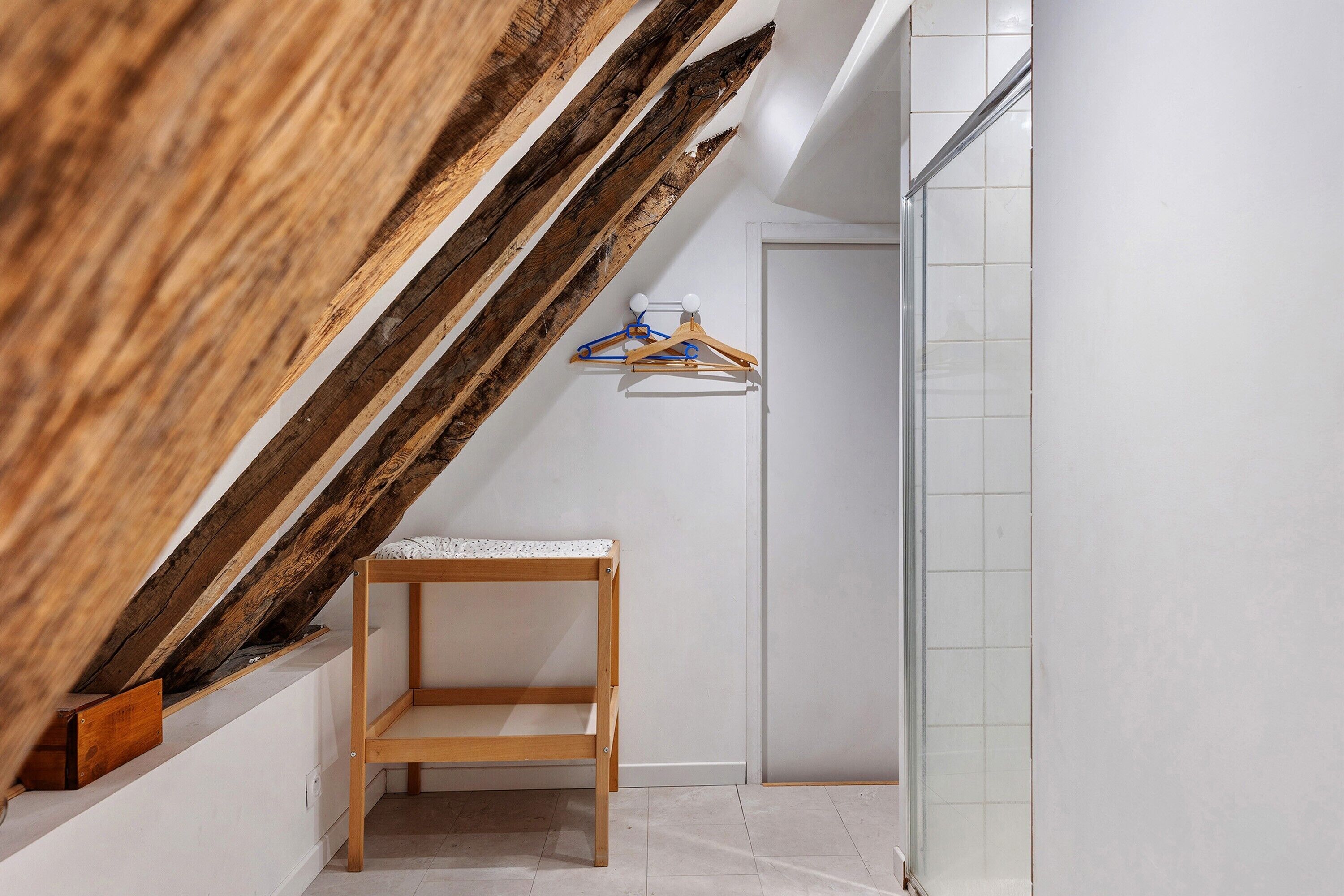 Ein kleines Holzregal in einer Ecke eines Raumes mit weißen Wänden und einem gefliesten Boden.