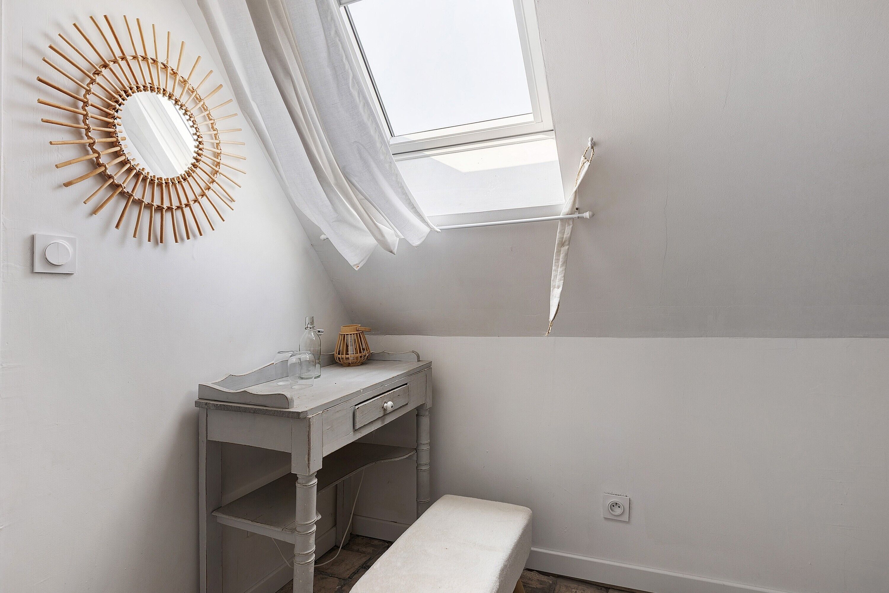Een badkamer met een wastafel, een spiegel, een raam en een bankje.