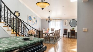 Un'area pranzo con un pianoforte, un lampadario e una scalinata.