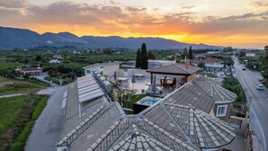 A residential area with a prominent building featuring a curved roof and a central courtyard with a hot tub. - Enclave Luxury Apartments Zante Experience equiped with Jacuzzi,BBQ,GYM (Zakinthos)