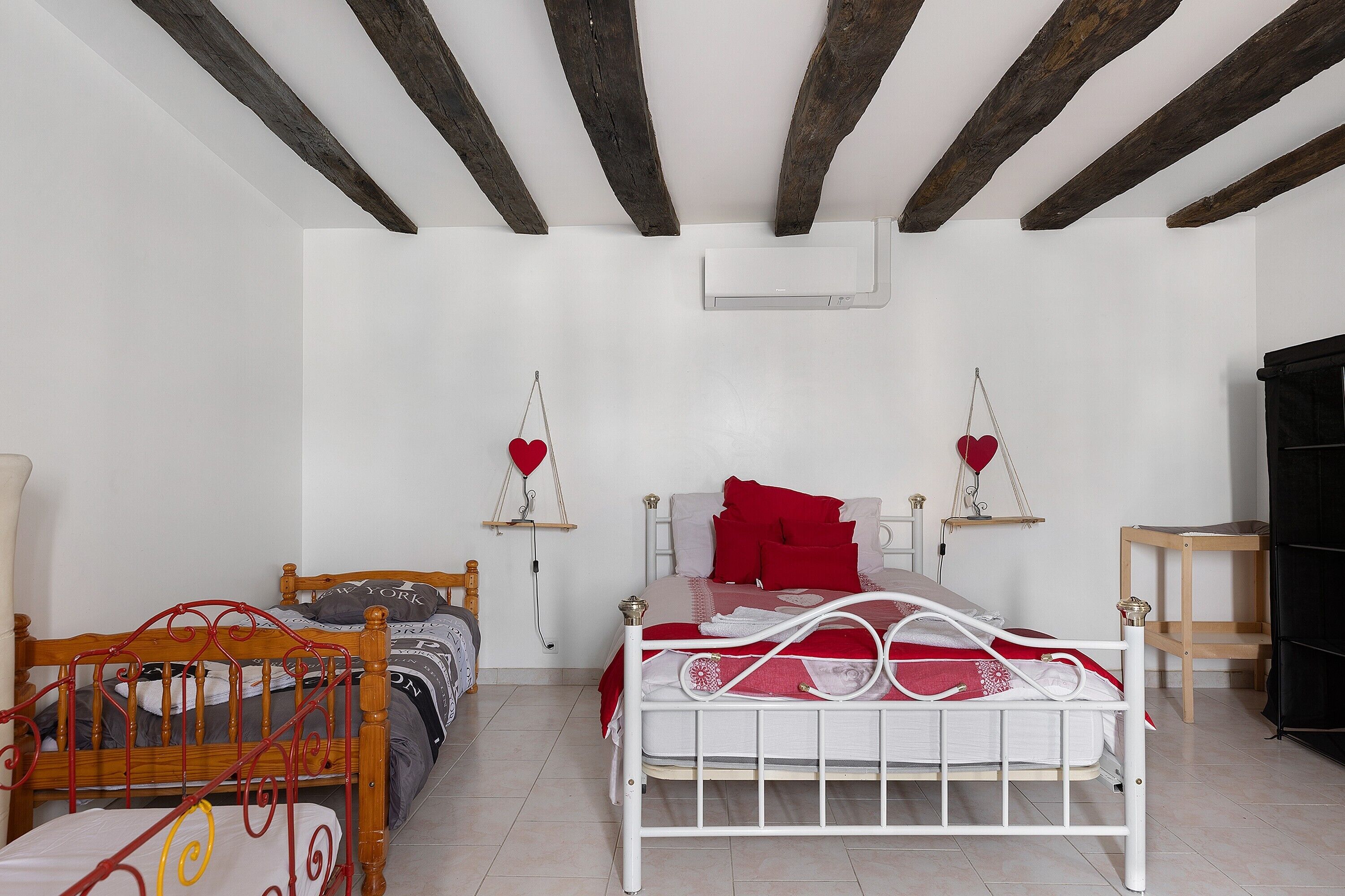 Een slaapkamer met twee bedden, een houten stoel, een zwarte kast en een witte airconditioning aan de muur.