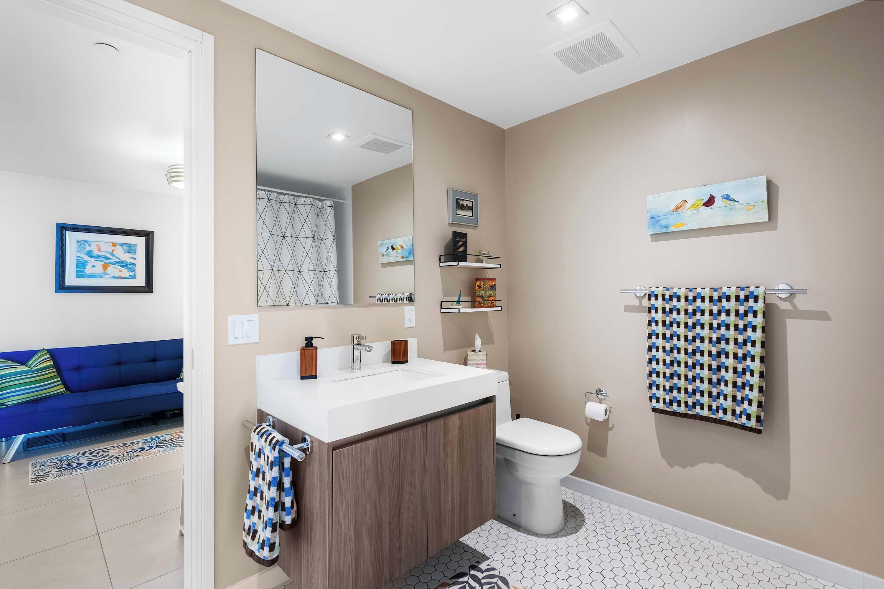 A bathroom with a white sink, a toilet, a mirror, and a towel rack.
