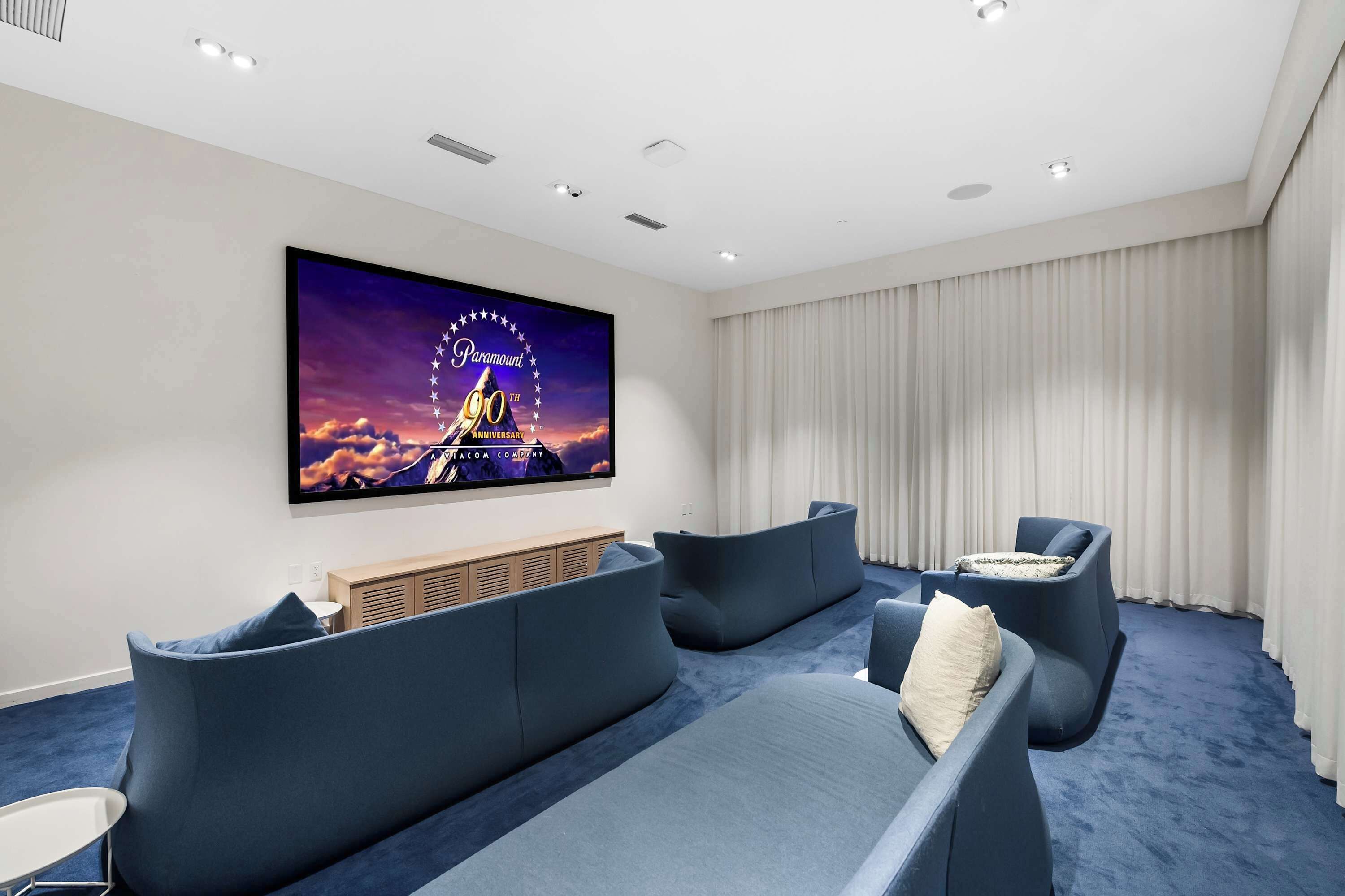 A modern cinema room with a large screen, comfortable seating, and a neutral color palette.