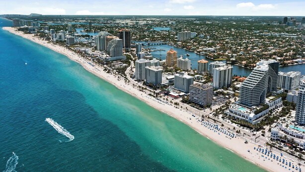 An aerial view of a coastal city with high-rise buildings, a beach, and a marina. - Bayside Breeze - Resort Access (Fort Lauderdale)