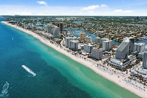 An aerial view of a coastal city with high-rise buildings, a beach, and a marina. - Beachside Breeze - Resort Access (Fort Lauderdale)