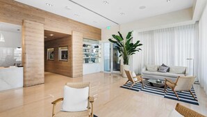 A modern lobby with a reception desk, seating area, and a large potted plant. - Bayside Breeze - Resort Access (Fort Lauderdale)