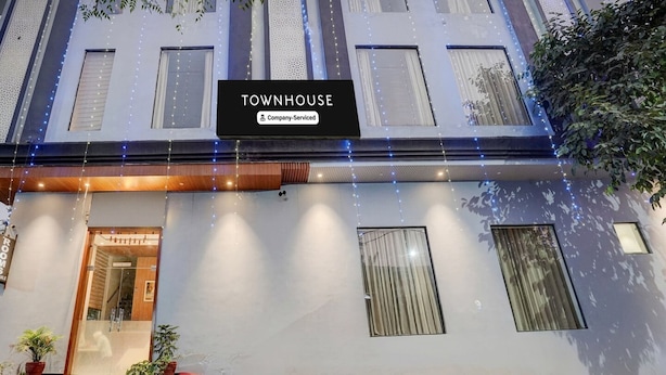 Um edifício de vários andares com uma placa que diz 'TOWNHOUSE Company-Serviced'.