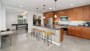 Une cuisine moderne avec des meubles en bois, des appareils électroménagers en acier inoxydable et des luminaires suspendus.