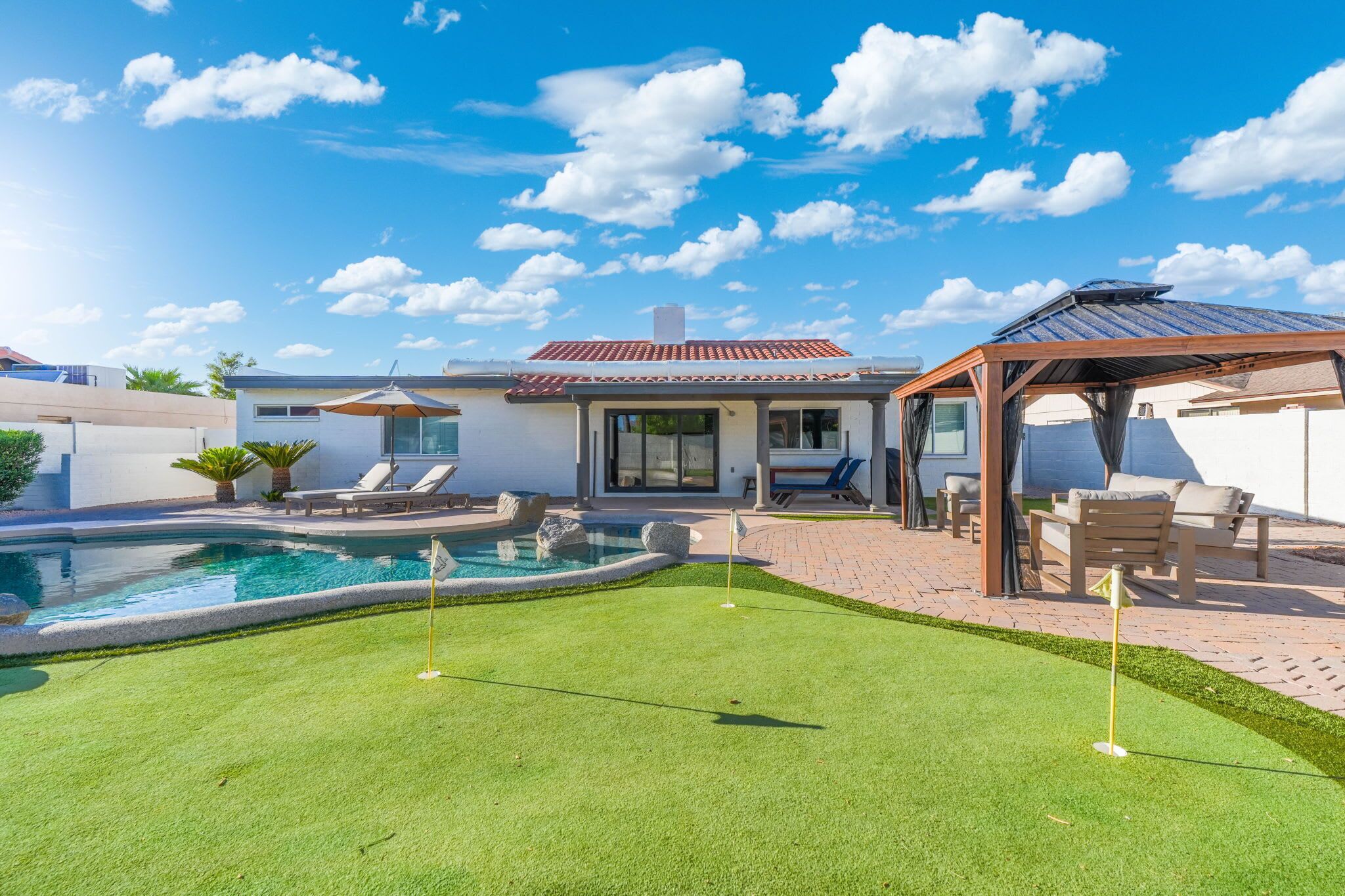 Un jardin avec une piscine, un espace patio et un coin salon abrité.