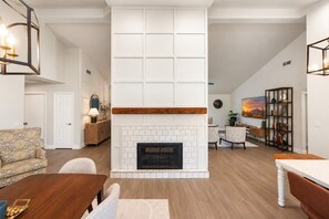 A modern living room with a fireplace, a dining area, and a seating space. - NEW | Sonoran Sol |Modern Pool Oasis Near Kierland (Scottsdale)