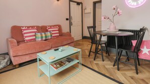 A cozy living room with a sofa, coffee table, and a dining area with chairs and a table. - Apartment Pink (Whitby)