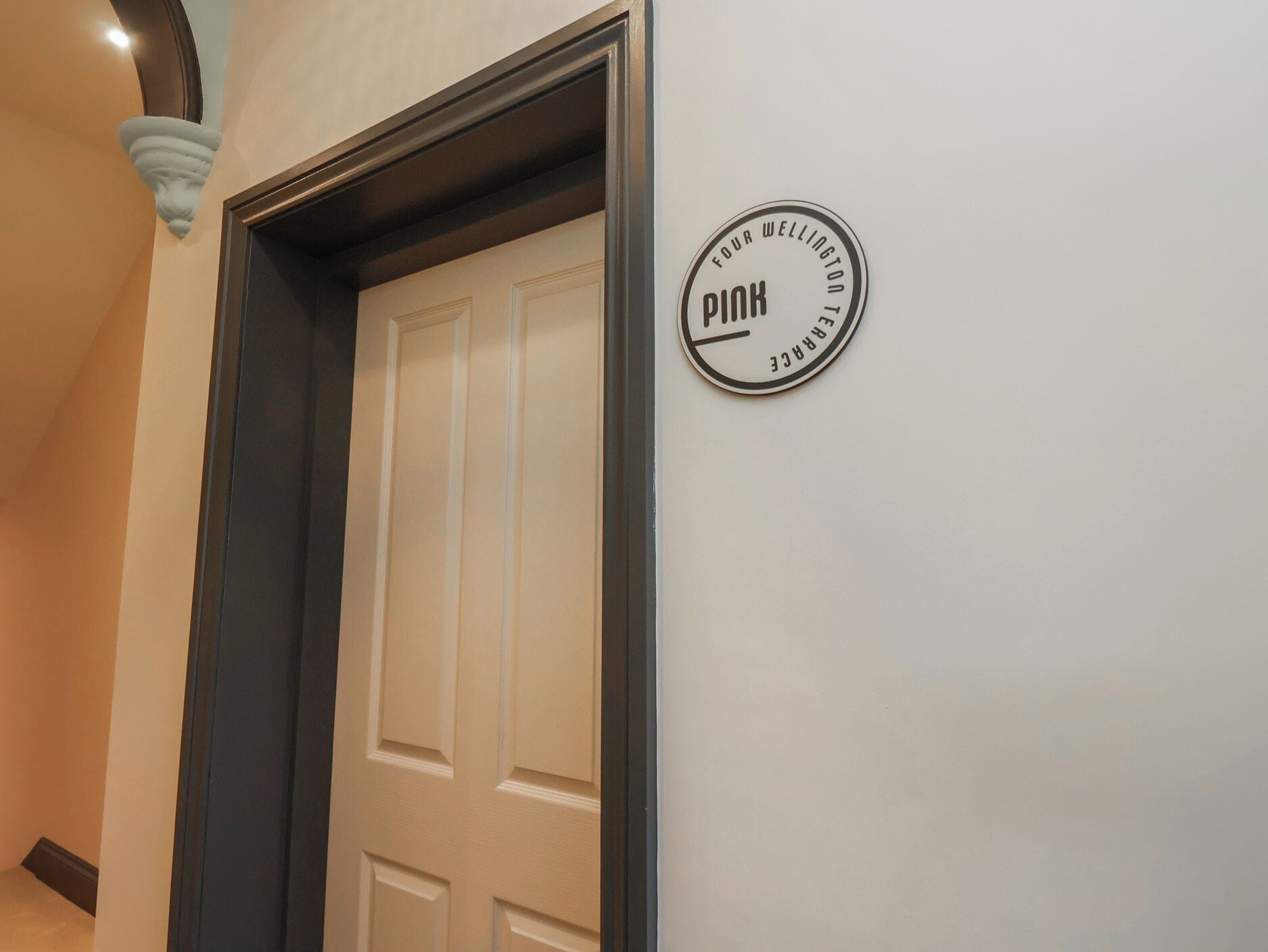 A door with a circular sign on the wall beside it.