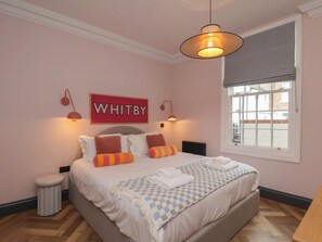 A bedroom with a bed, a window, a radiator, and a sign on the wall. - Apartment Pink (Whitby)