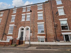 A red brick building with a white door, multiple windows, and a black metal fence. - Apartment Pink (Whitby)