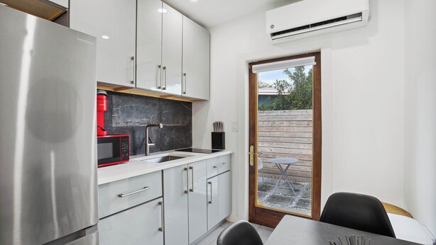 Una cocina moderna con electrodomésticos de acero inoxidable, armarios blancos y un comedor con mesa y sillas.