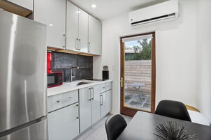Una cocina moderna con electrodomésticos de acero inoxidable, armarios blancos y un comedor con mesa y sillas.