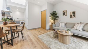 En modern inredning med ett matområde, en soffa och ett litet sidobord med en växt.