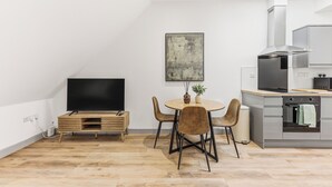 Ett modernt kök med en matplats, en platt-TV och en tavla på väggen.