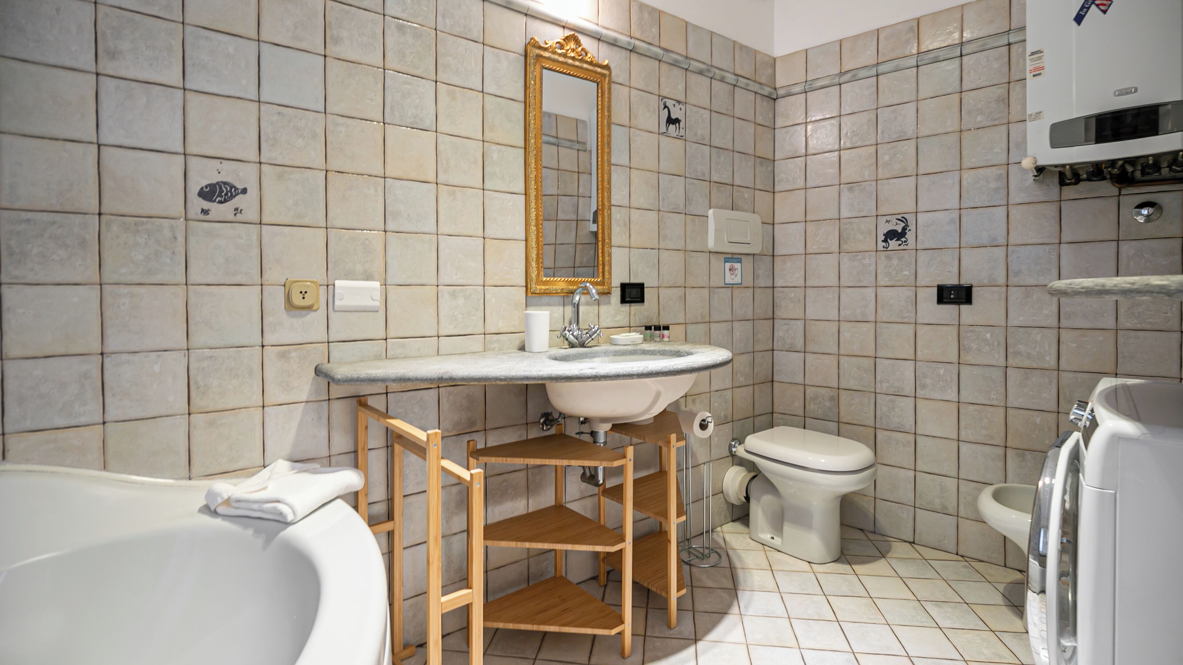 Un bany amb banyera, un lavabo amb mirall, un vàter i una dutxera.