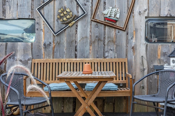 A rustic wooden wall with a framed ship model, a ship model on a shelf, and a wooden bench with cushions. - Tiny Home with Private Terrace on the Mönchgut Peninsula (Mönchgut)