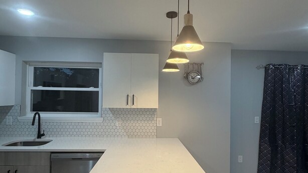 Una cocina moderna con una isla grande, iluminación colgante y una ventana sobre el lavamanos.