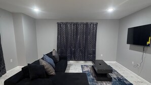 Una sala de estar moderna con un sofá seccional, un televisor de pantalla plana y una cortina estampada.