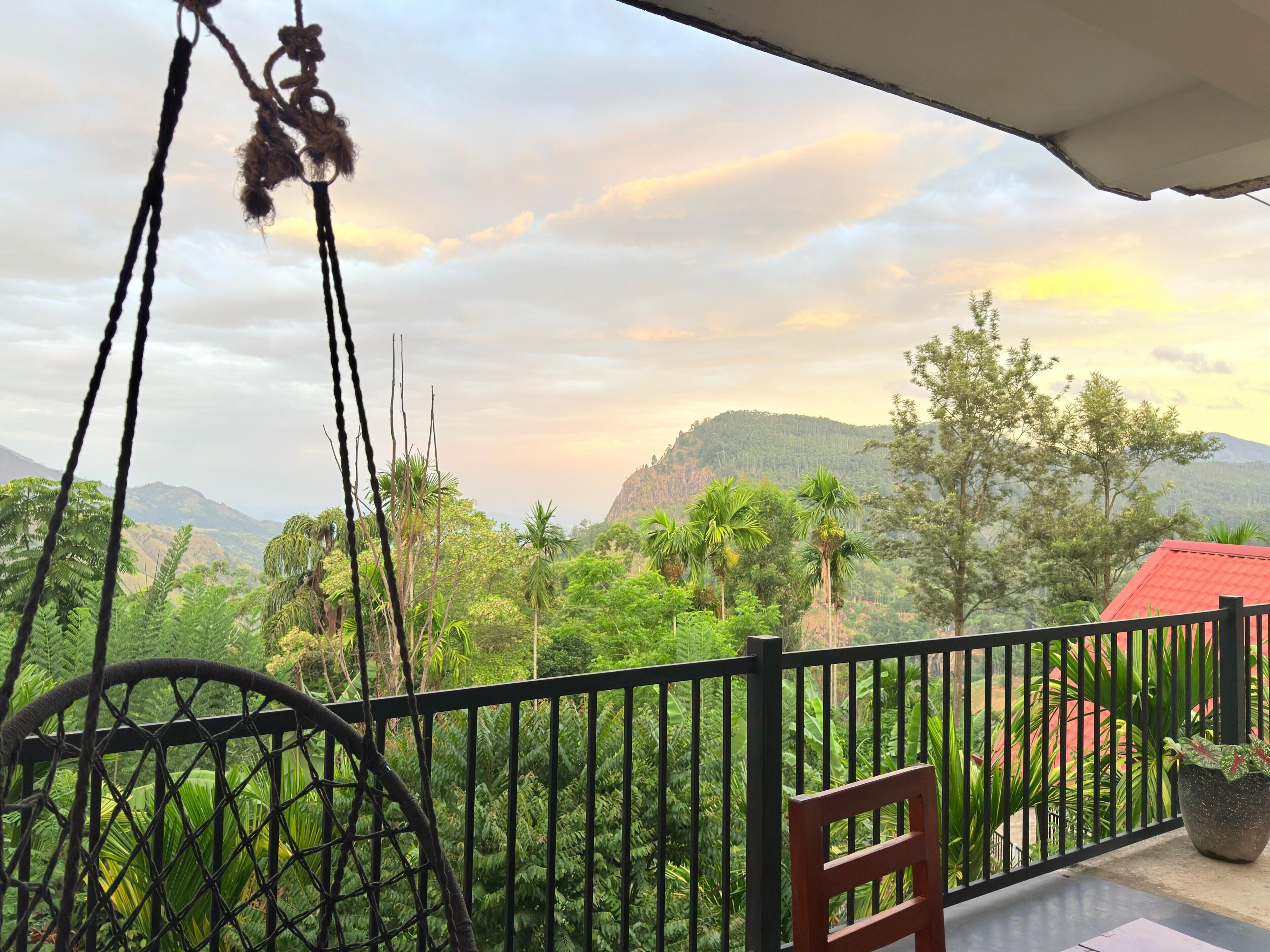 A balcony with a view of a lush landscape, including trees and hills.