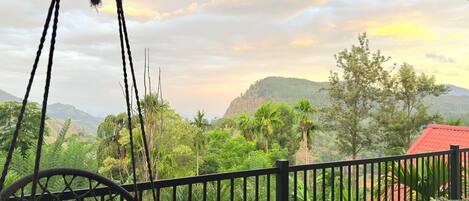 A balcony with a view of a lush landscape, including trees and hills.