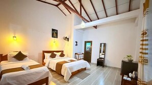 A hotel room with two beds, a wooden ceiling, a flat-screen TV, and a small plant.