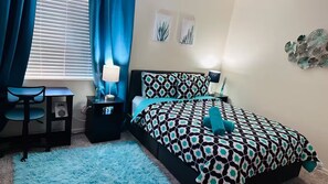A bedroom with a bed, a desk, a chair, a lamp, and a blue rug. - Tranquil Oasis Retreat. (Sierra Vista)