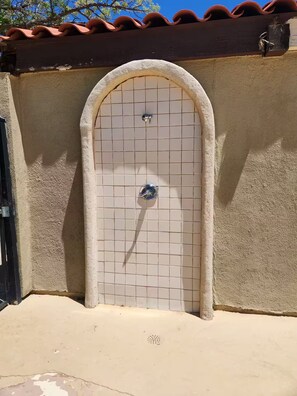 A tiled door with a metal handle, set in a textured wall with a red-tiled roof above. - Tranquil Oasis Retreat. (Sierra Vista)