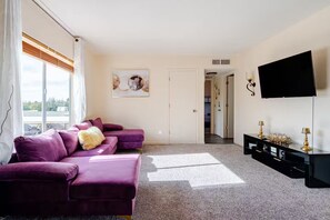A modern living room with a purple sofa set, a flat-screen TV, and a decorative wall piece. - Tranquil Oasis Retreat. (Sierra Vista)