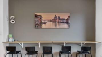 Eine Wand mit einem Stadtbildgemälde, einer weißen Steckdose und einem Regal mit Büchern und einer kleinen Schachtel.