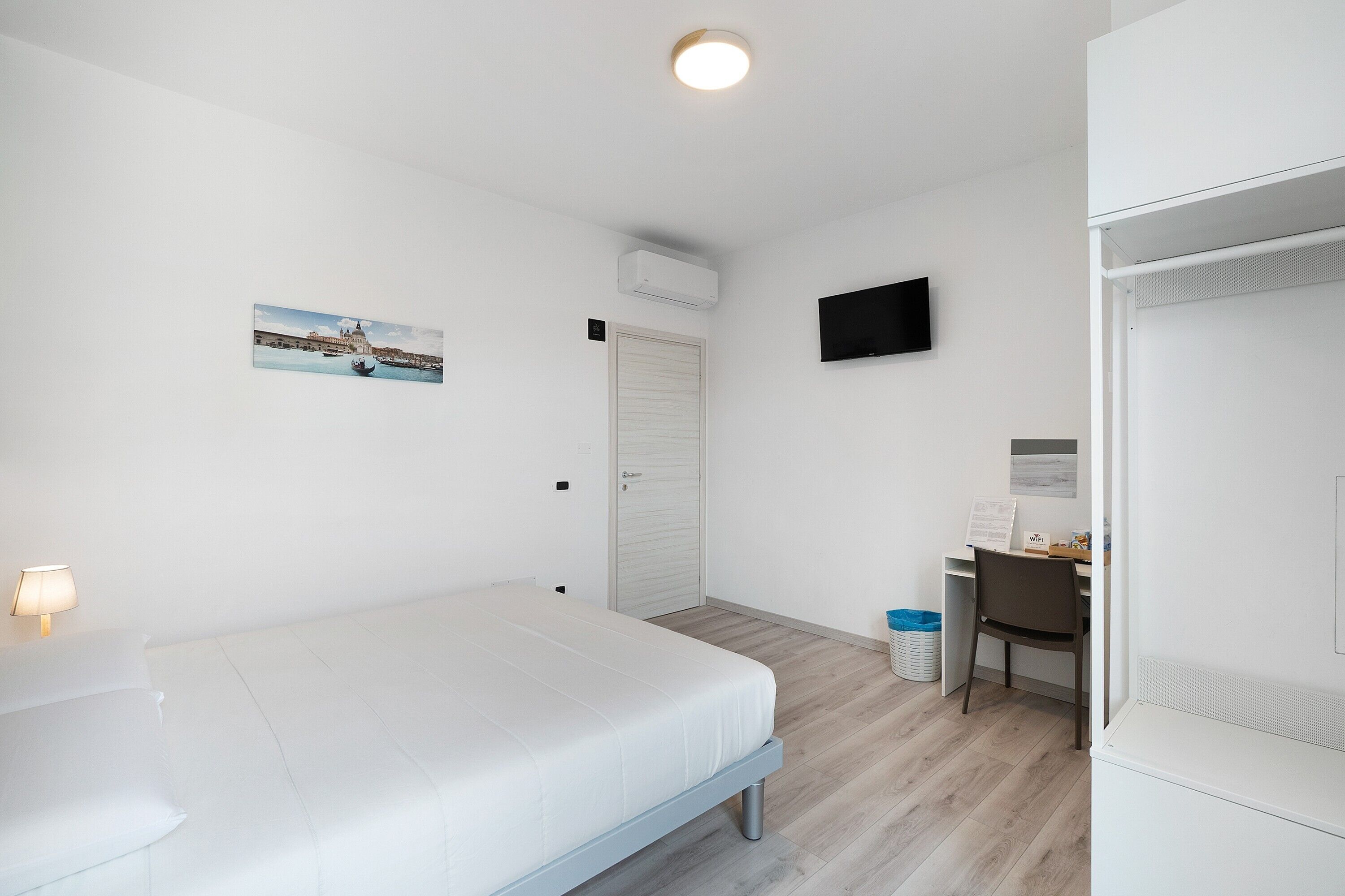 Een hotelkamer met een bed, een bureau, een stoel, een televisie en een schilderij aan de muur.