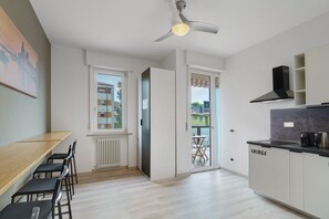 Une cuisine moderne dotée d’un réfrigérateur encastré, un coin repas avec une table et des chaises, et une fenêtre donnant sur l’extérieur.